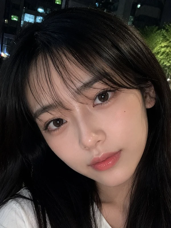 Close-up street portrait of a woman in a white shirt at night
